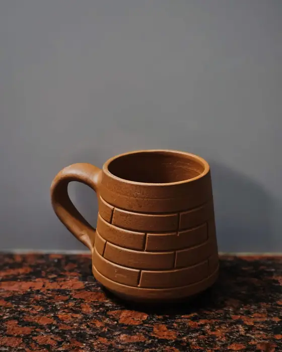 Taza de barro con asa tirada, con una línea incisa alrededor del cuerpo, sobre una encimera de granito