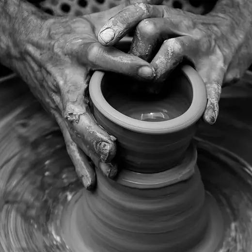 Primer plano en blanco y negro de unas manos centrando el barro en el torno